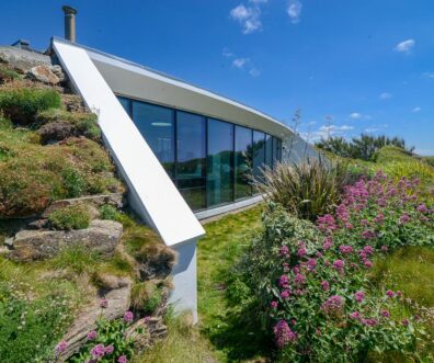 Exterior picture of the large window to the side of Spin with views out towards the ocean from the living room and the open plan kitchen and dining area