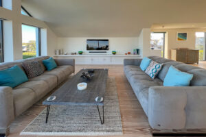 First floor lounge area with large sofas and mounted TV