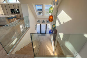 Staircase leading from first floor with glass balustrades at Cornerstones