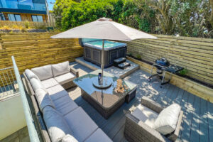 Rear decked garden at No 1 Treglos Gardens with seating, parasol, BBQ and hot tub