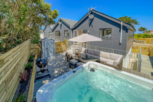 Rear exterior view of the decking at No 1 Treglos Gardens with seating, BBQ and hot tub