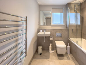 Main bathroom with loo, basin, bath tub and overhead shower at No 1 Treglos Gardens