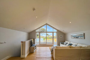 First floor lounge with corner sofa and TV at No 1 Treglos Gardens