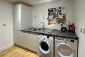 Utility room at Morwynsow with sink, washing machine and tumble dryer