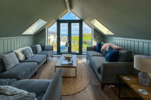 The second floor sitting room with plenty of comfortable seating and double door onto balcony with views toward the ocean
