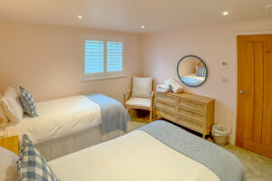 The ensuite twin bedroom on the ground floor at Tremblze with chair and chest of drawers