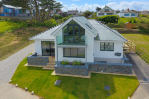 The front exterior at Tremblaze with grassed lawn, driveway and double doors to the open plan dining area and neighbouring properties to the rear