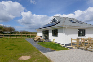 The rear exterior at Tremblaze with wooden picnic bench on he patio and wooden fencing around the garden