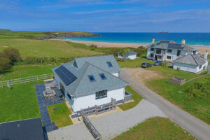 Aerial view over Tremblaze and a neighbouring property toward Harlyn Bay beach and over the ocean