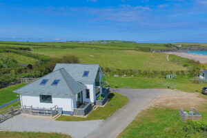Aerial view over Tremblaze with fields and coastal footpath to one side of he side of the house and Trevose Head in the distance