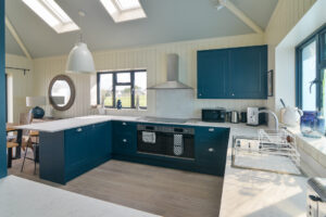 The kitchen area at Tremblaze with breakfast bar and appliances and windows to the front and side of the house