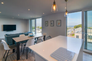 The open plan living area at The View with kitchen island, dining table and chairs and seating and tv in the lounge area