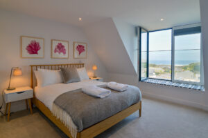 The second floor master ensuite king bedroom at The View with large window and views towards the ocean and Trevose Head