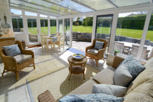 Sunny conservatory with seating and doors onto patio area to the rear of Zefyros