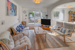 Lounge area at No 8 Sandhills with TV, ample seating and doors out to the rear paved area with outside furniture
