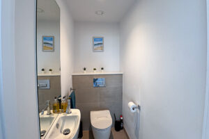 Cloakroom on the first floor with a toilet, basin and wall-mounted mirror.