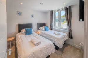 Twin bedroom with window and wall mounted television at No 2 Treglos