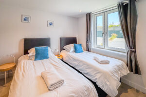 Twin bedroom with window and wall mounted television at No 2 Treglos