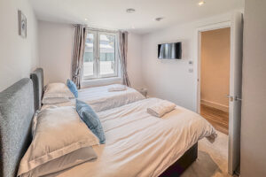 Twin bedroom with window and wall mounted television at No 2 Treglos
