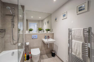 Bathroom with bath, overhead shower, toilet, basin and wall mounted mirror at No 2 Treglos