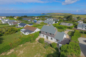 Aerial view over Whitehaven with nearby properties and view towards the ocean over the golf course toward Trevose Head