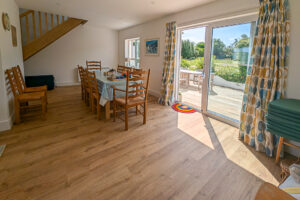 Dining area with table and chairs and sliding doors onto the rear decking at Whitehaven
