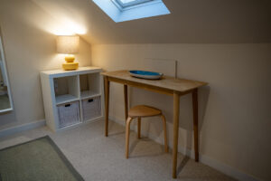 A console table on the landing with a stool under a skylight at Iona